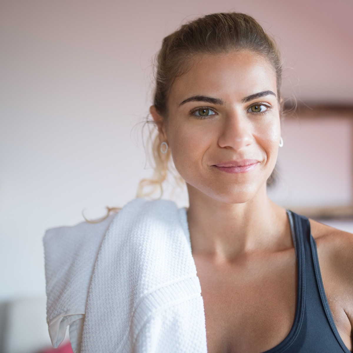 A woman with a towel over her shoulder after a session, smiling a small honest smile.